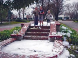 Three children clean soap from fountain