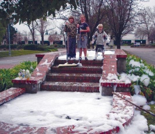 Three children clean soap from fountain